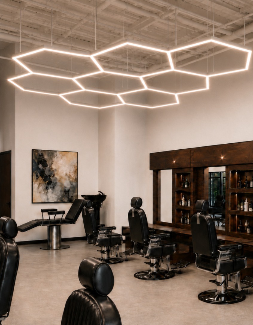 Interior — hexagon ceiling lights above barber chairs and a wood-panelled mirror wall